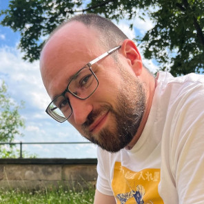 A picture of me, a bald man with a short beard, wearing glasses and smiling at the camera in an outdoor setting